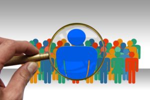 A magnifying glass over stick figures.